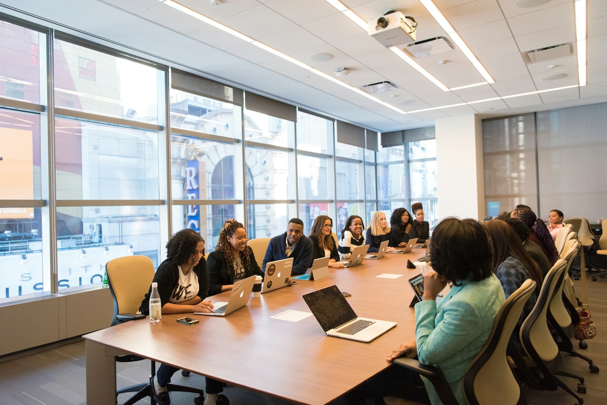 Professionals coordinating around a conference table with laptops